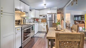 A modern kitchen with white cabinets, stainless steel appliances, and a wooden dining table.