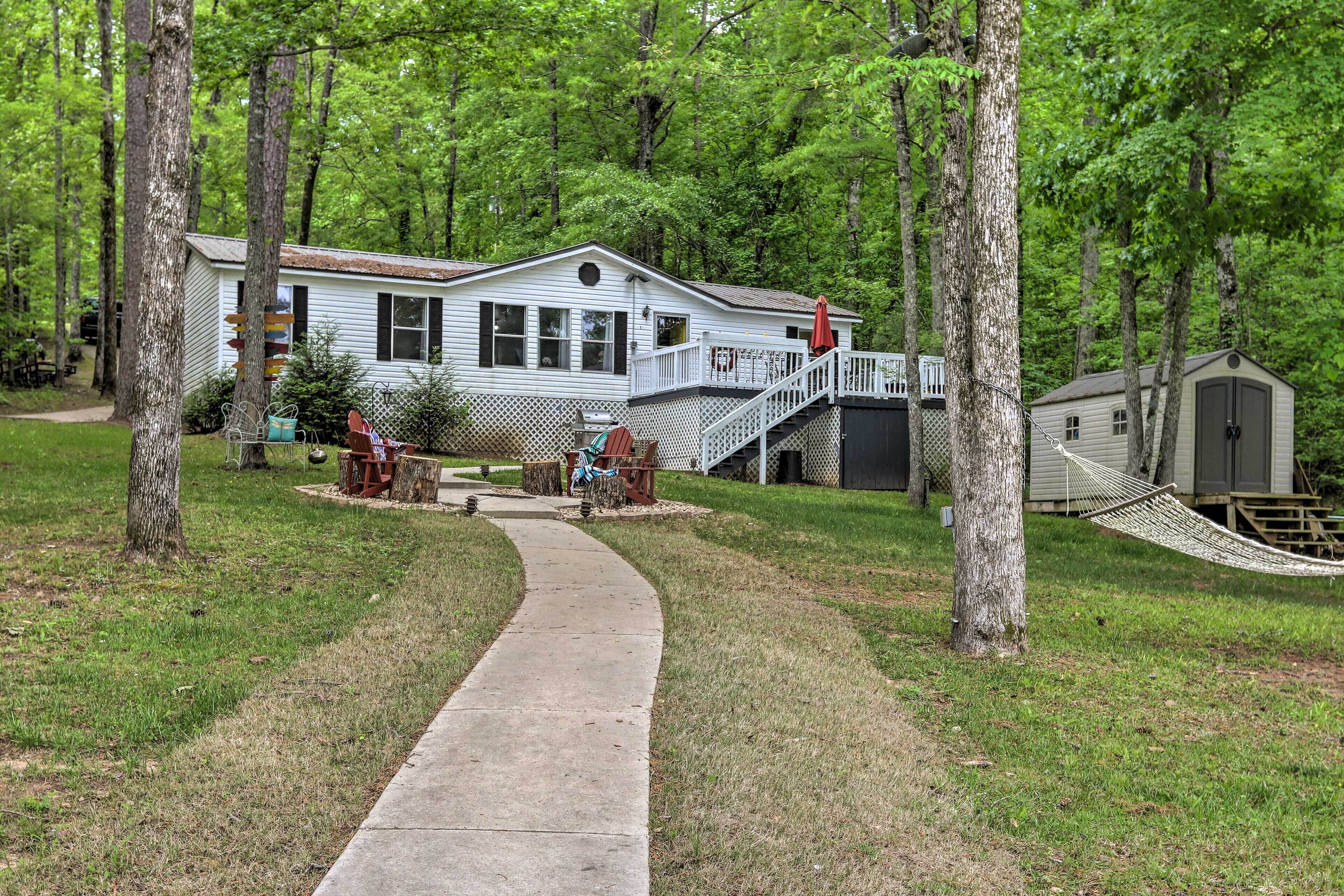 A cabin with a deck, a hammock, and a pathway leading to the house.