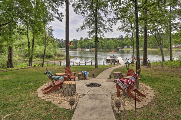 A lakeside patio with Adirondack chairs, a fire pit, and a view of the lake. - Lakefront Sparta Home: Fire Pit, Dock & Kayak (Milledgeville)