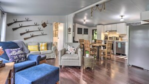 A living room with a blue sofa, a patterned armchair, and a dining area with a wooden table and chairs.