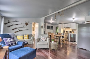 A living room with a blue sofa, a patterned armchair, and a dining area with a wooden table and chairs.