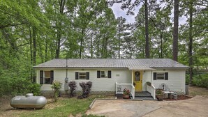 A single-story house with a front porch, a yellow door, and a small front yard with potted plants.