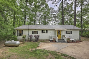 A single-story house with a front porch, a yellow door, and a small front yard with potted plants.