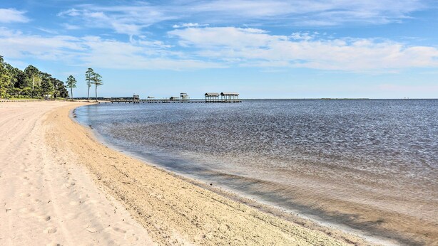 A beach with a wooden pier extending into calm waters, surrounded by trees and a clear sky. - Ocean Springs Home w/ Bikes < 1 Mile to Beach! (Ocean Springs)