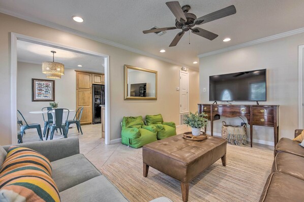 A spacious living room with a ceiling fan, a large flat-screen TV, and a dining area with a table and chairs.