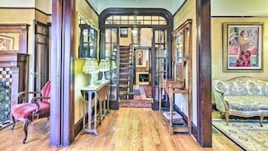 A hallway with wooden flooring, a red chair, a sofa, and a staircase leading to another room. - Historical Portland Home < 2 Mi to Downtown! (Portland)