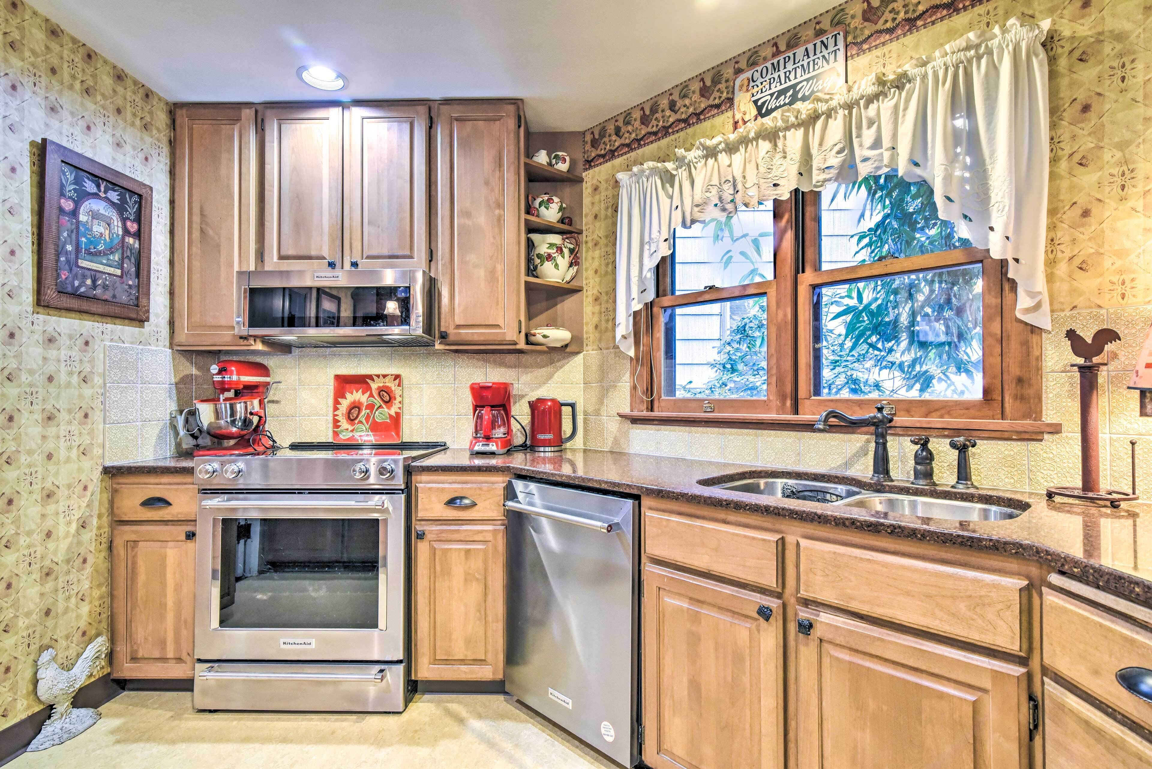 A kitchen with wooden cabinets, a built-in oven, a dishwasher, and a window with curtains.
