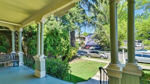 A covered porch with columns, a bench, and a view of a street with parked cars and houses. - Historical Portland Home < 2 Mi to Downtown! (Portland)