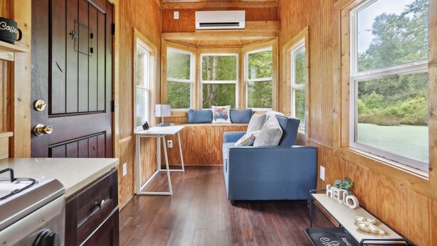 A cabin with a kitchenette, a sofa, a window seat, and a view of the outdoors. - Pendergrass Tiny Home Cabin on Pond w/ Fire Pit! (Pendergrass)