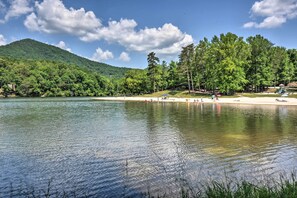 A lake with a forested hillside, a sandy beach, and a playground. - Jasper Vacation Rental w/ Decks, Fire Pit & Views! (Jasper)