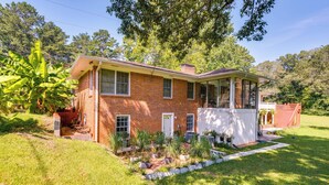 A two-story brick house with a porch, surrounded by a well-maintained garden and a red barn in the background. - ~ 13 Mi to Atlanta: Private Stone Mountain Getaway (Stone Mountain)