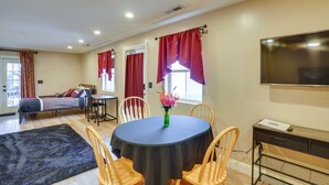A room with a bed, a dining table with chairs, a TV mounted on the wall, and a window with curtains. - Convenient Cedar City Studio < Half-mi to Downtown (Cedar City)