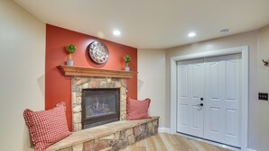 A room with a stone fireplace, a red wall, and a white door. - Convenient Cedar City Studio < Half-mi to Downtown (Cedar City)