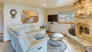 A living room with a stone fireplace, a leather sofa, a coffee table, and a television. - Deck & Beach Access: Lake Tahoe Shoreside Retreat! (Zephyr Cove)