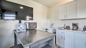 Una cocina compacta equipada con televisión de pantalla plana, ventilador, cafetera y lavadora.