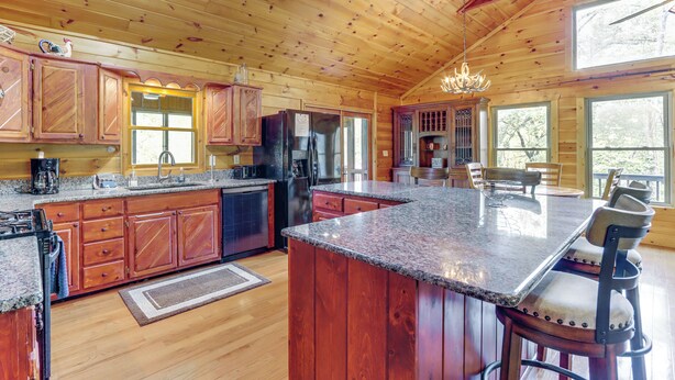 A spacious kitchen with wooden cabinets, granite countertops, and a large island. - Riffle Run Cabin: River Access, Hot Tub, Game Room (Ellijay)