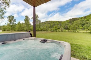 A hot tub with a wooden pergola overhead, surrounded by a grassy lawn and trees. - Riffle Run Cabin: River Access, Hot Tub, Game Room (Ellijay)