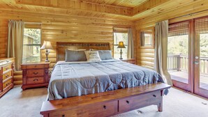 A wooden cabin bedroom with a bed, nightstands, and a bench. - Riffle Run Cabin: River Access, Hot Tub, Game Room (Ellijay)