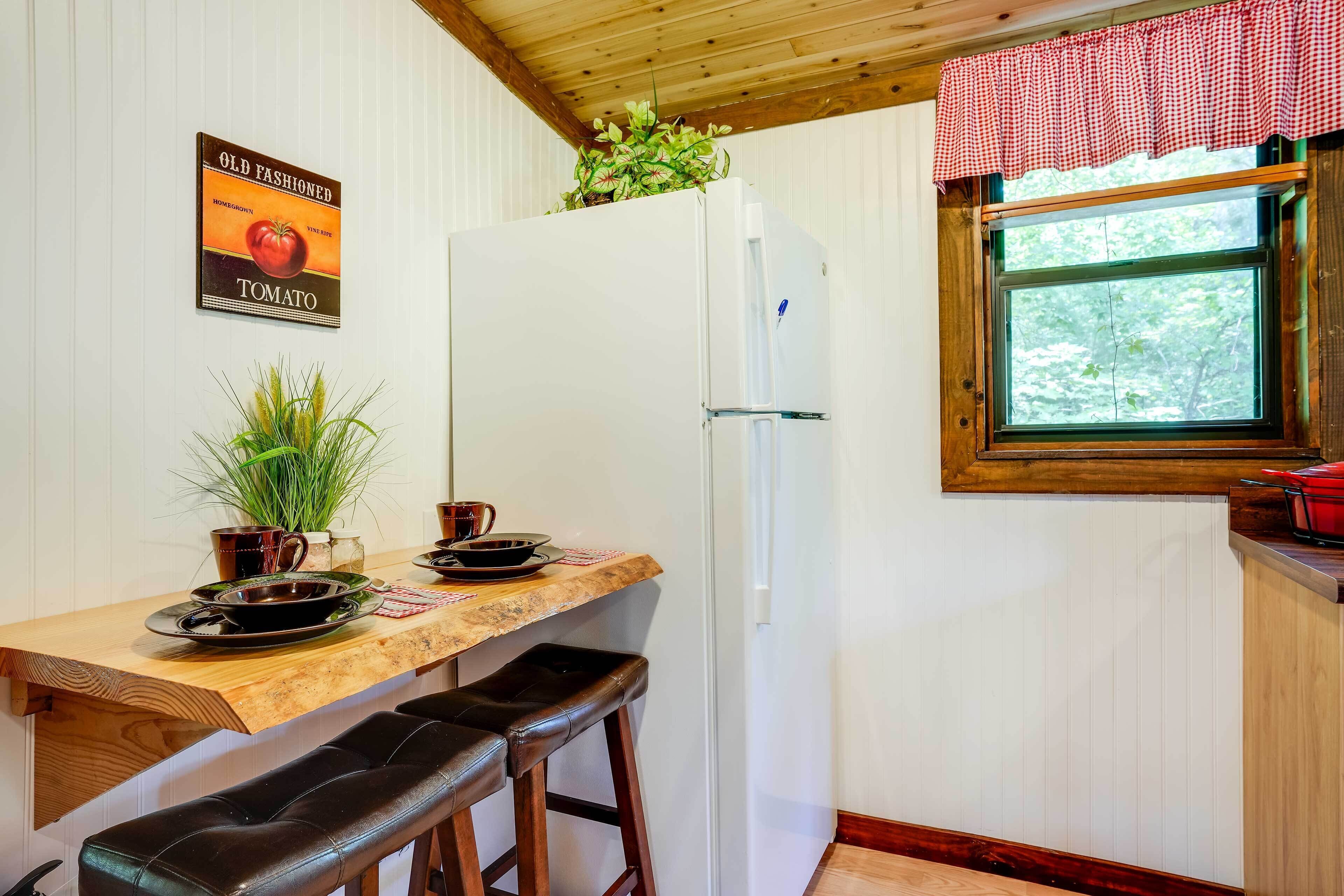 A kitchen with a wooden countertop, a white refrigerator, and a window with a view of trees.