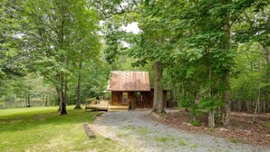 A rustic cabin with a wooden deck, surrounded by trees in a wooded area. - Cozy Georgia Abode w/ Deck, Fire Pit & Lake Access (Menlo)