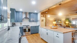 Une cuisine moderne avec des meubles gris, un plafond en bois et un îlot central.