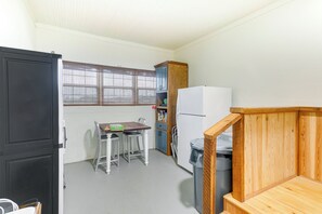 A compact kitchen with a table, chairs, a refrigerator, and a wooden cabinet. - Beautiful Georgia Farmhouse Rental w/ Patio (Lenox)