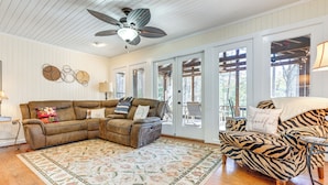 Uma sala de estar com um sofá seccional marrom, uma poltrona com estampa de zebra e um tapete floral.