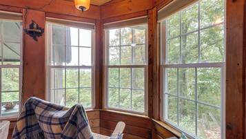 A cozy cabin with large windows, a plaid blanket, and a rustic wooden interior.