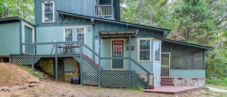 A two-story house with a stone foundation, a front porch, and a staircase leading to the upper level.