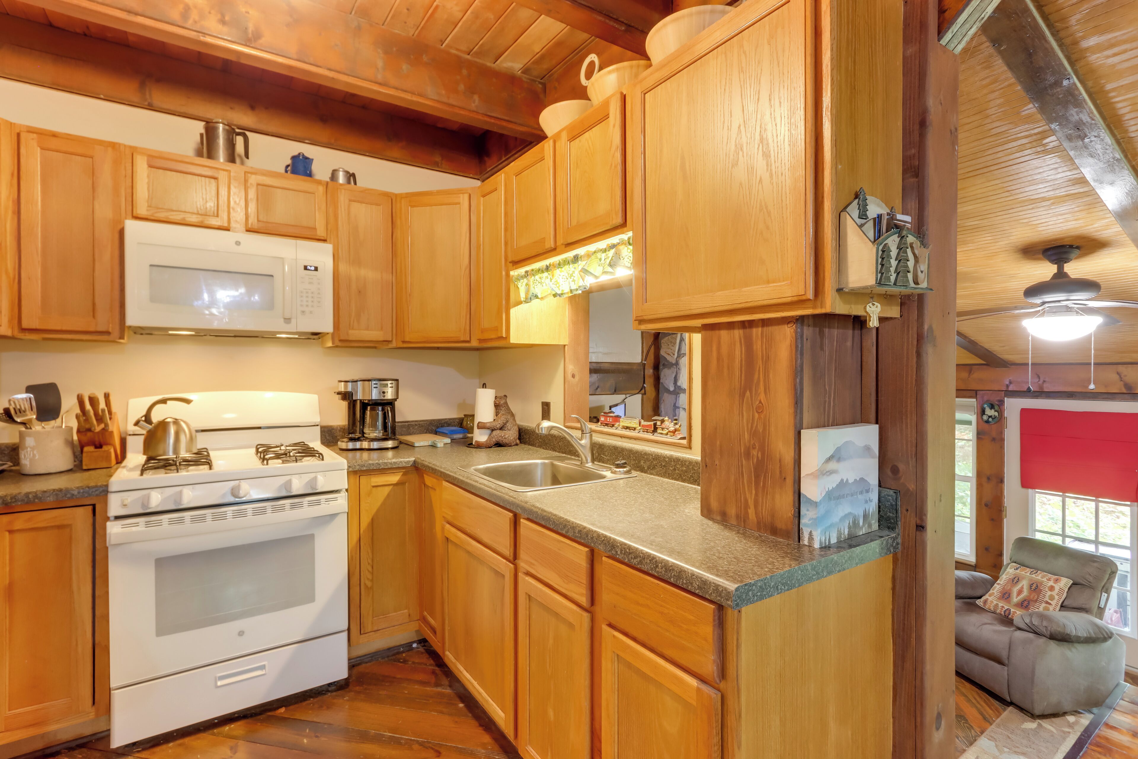 A kitchen with wooden cabinets, a stove, a microwave, and a sink.