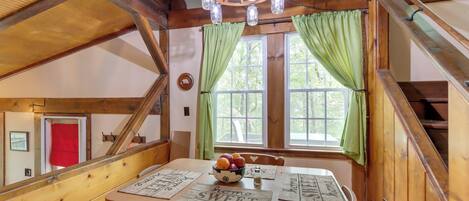 A wooden dining table with placemats, a bowl of fruit, and a chandelier.