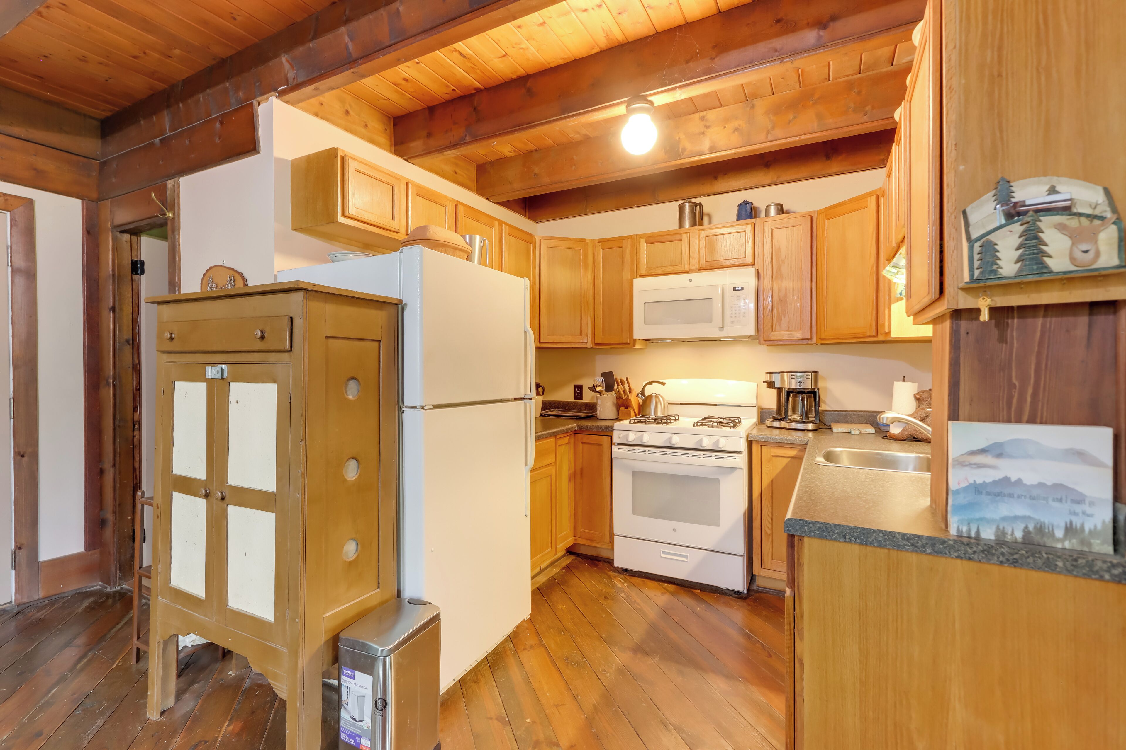 A kitchen with wooden cabinets, a refrigerator, a microwave, a stove, and a sink.