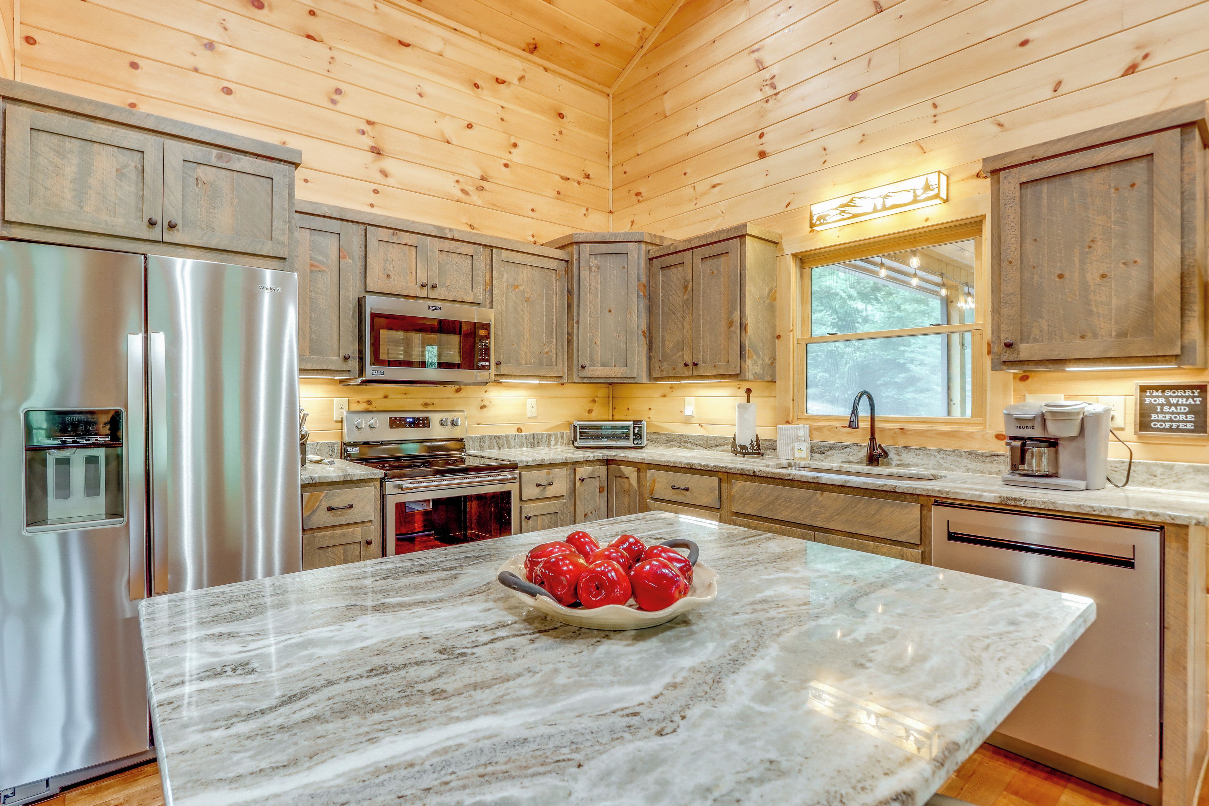 A kitchen with wooden cabinets, stainless steel appliances, and a marble countertop.