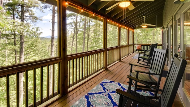 A covered porch with wooden railings, ceiling fans, and string lights.