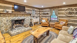 A cozy log cabin interior with a stone fireplace, wooden furniture, and rustic decor. - Cozy Creekside Mountain Escape w/ Hot Tub! (Sautee Nacoochee)