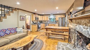 A spacious living area with a wooden bench, a sofa, and a fireplace. - Cozy Creekside Mountain Escape w/ Hot Tub! (Sautee Nacoochee)