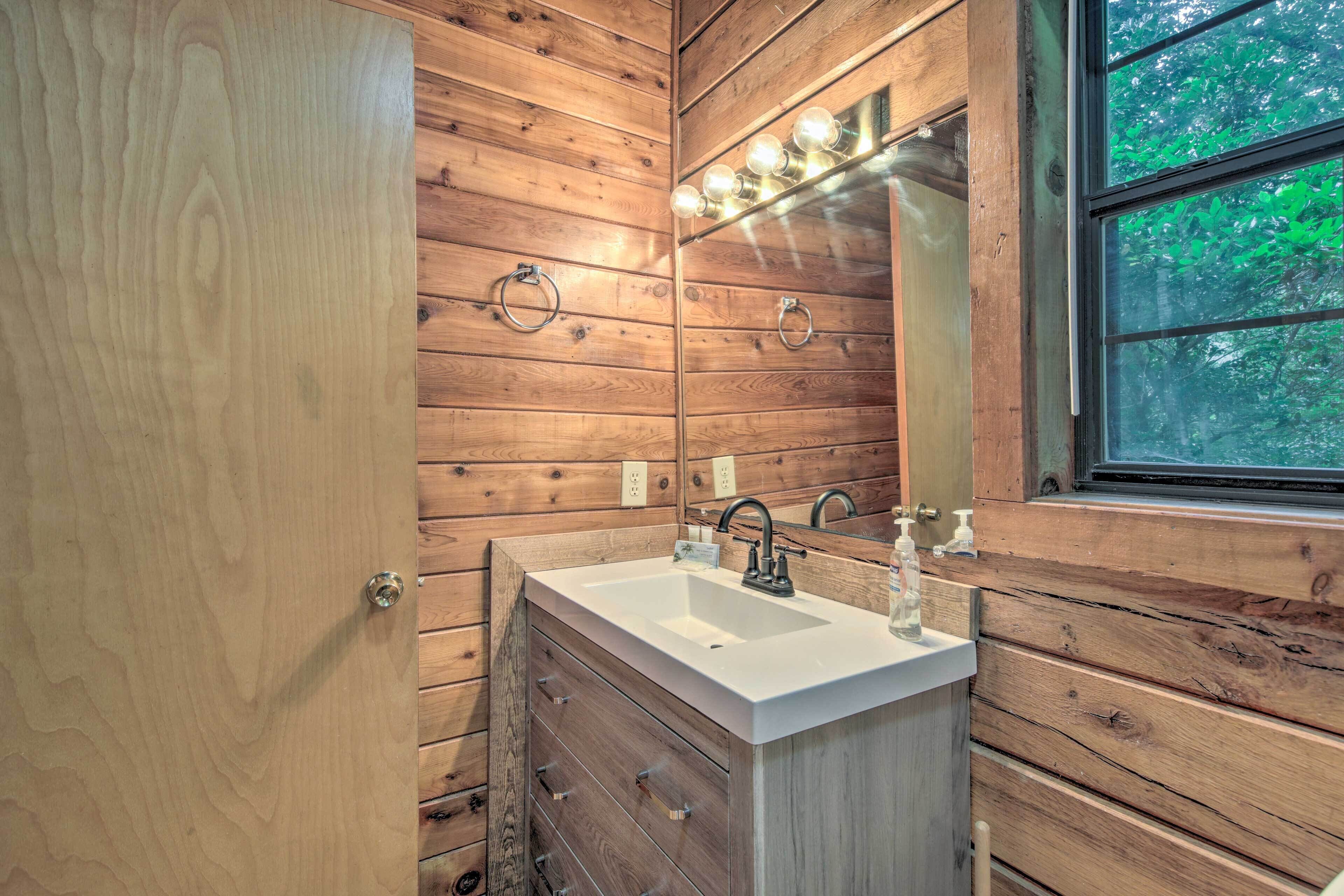 Un baño de madera con lavamanos, espejo y ventana.