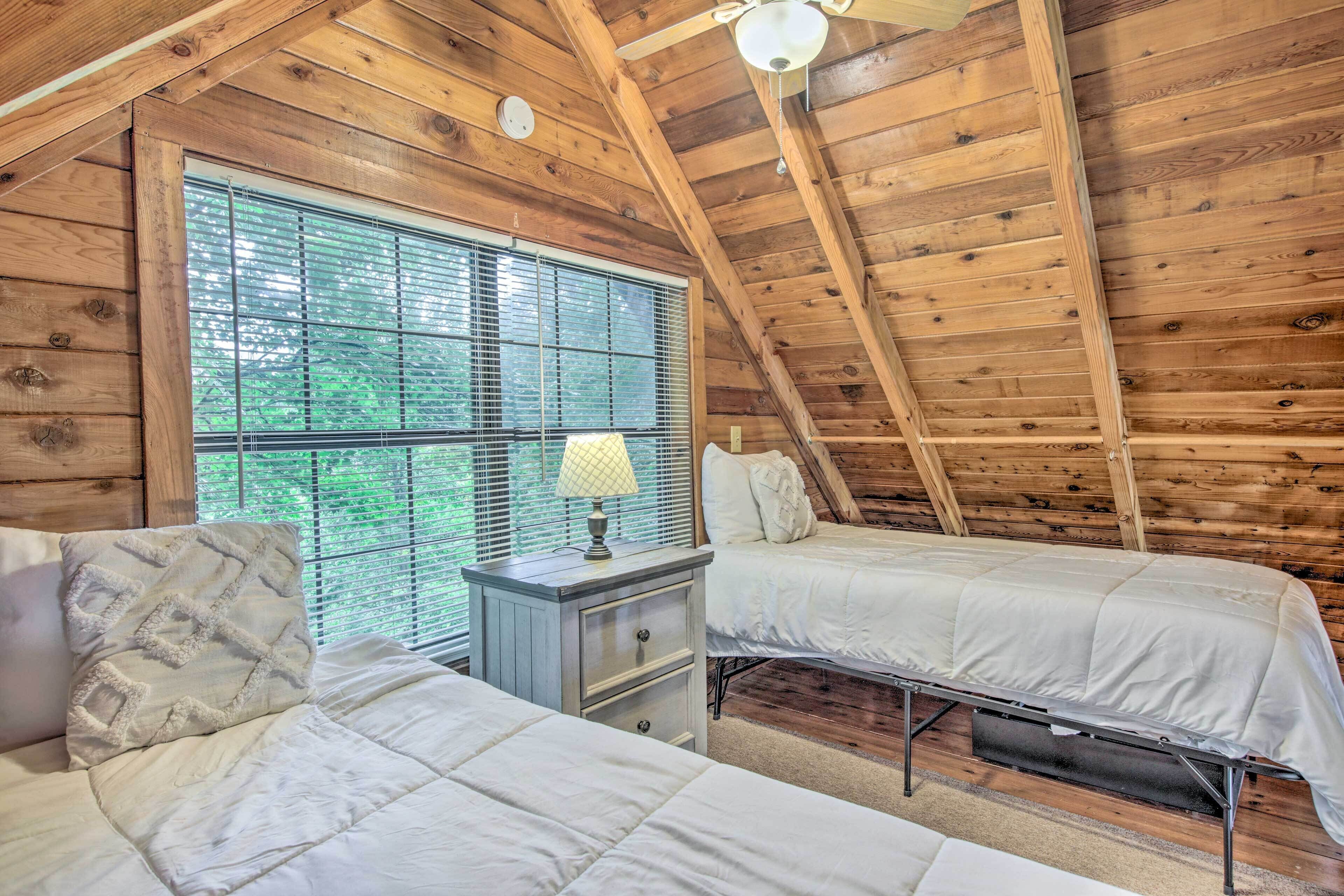 A cabin with two beds, a nightstand, and a window with blinds.