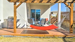 Une terrasse extérieure dotée d’une pergola en bois, d’un barbecue et d’un hamac.
