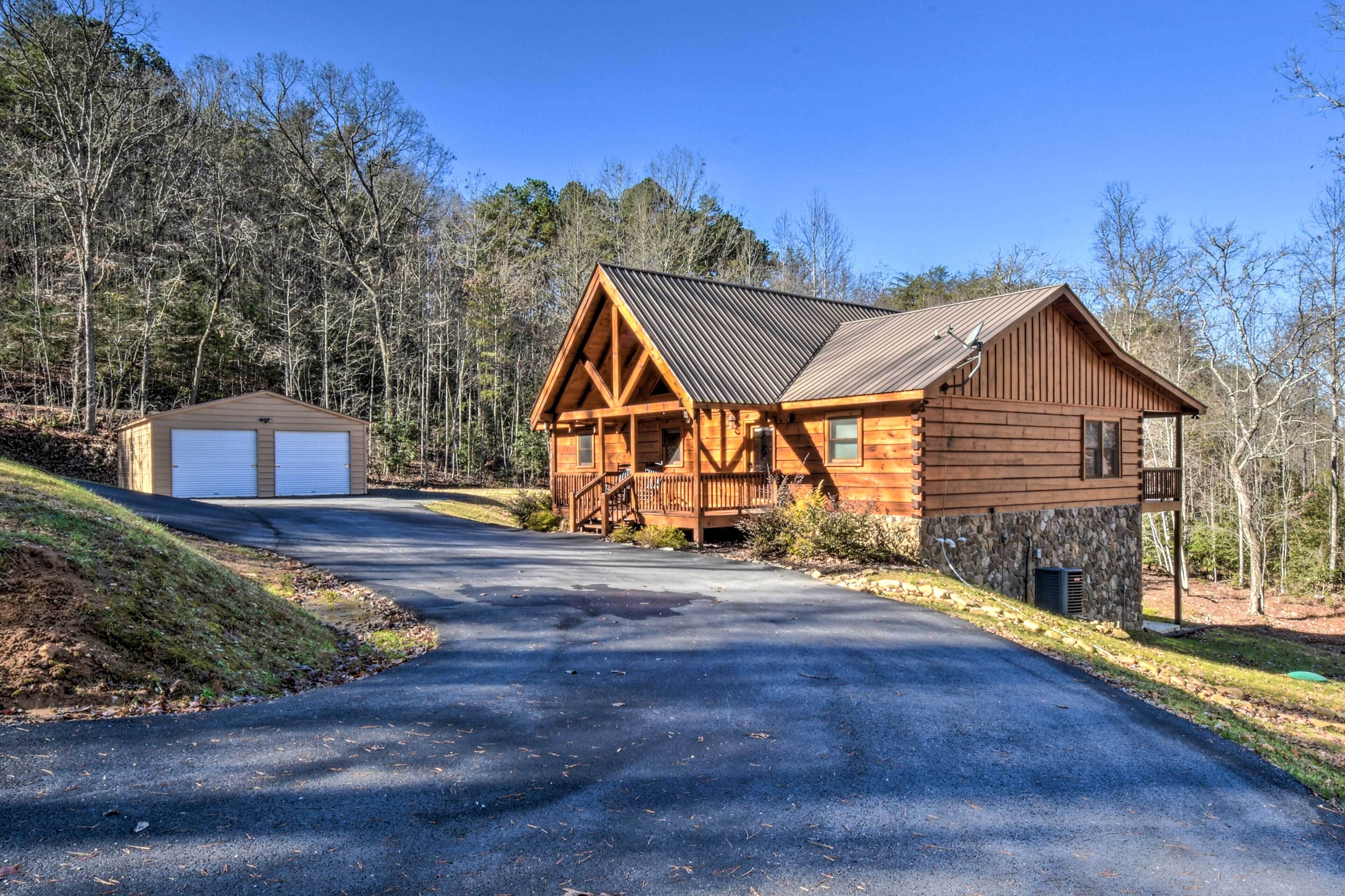 A log cabin with a metal roof, a front deck, and a garage.