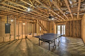 Une pièce spacieuse avec une table de ping-pong, des poutres en bois et une isolation du plafond apparente.