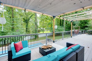 An outdoor deck with wicker furniture, a pergola, and a view of a wooded area. - Mableton Home w/ Private Pool ~ 15 Mi to Atl! (Mableton)