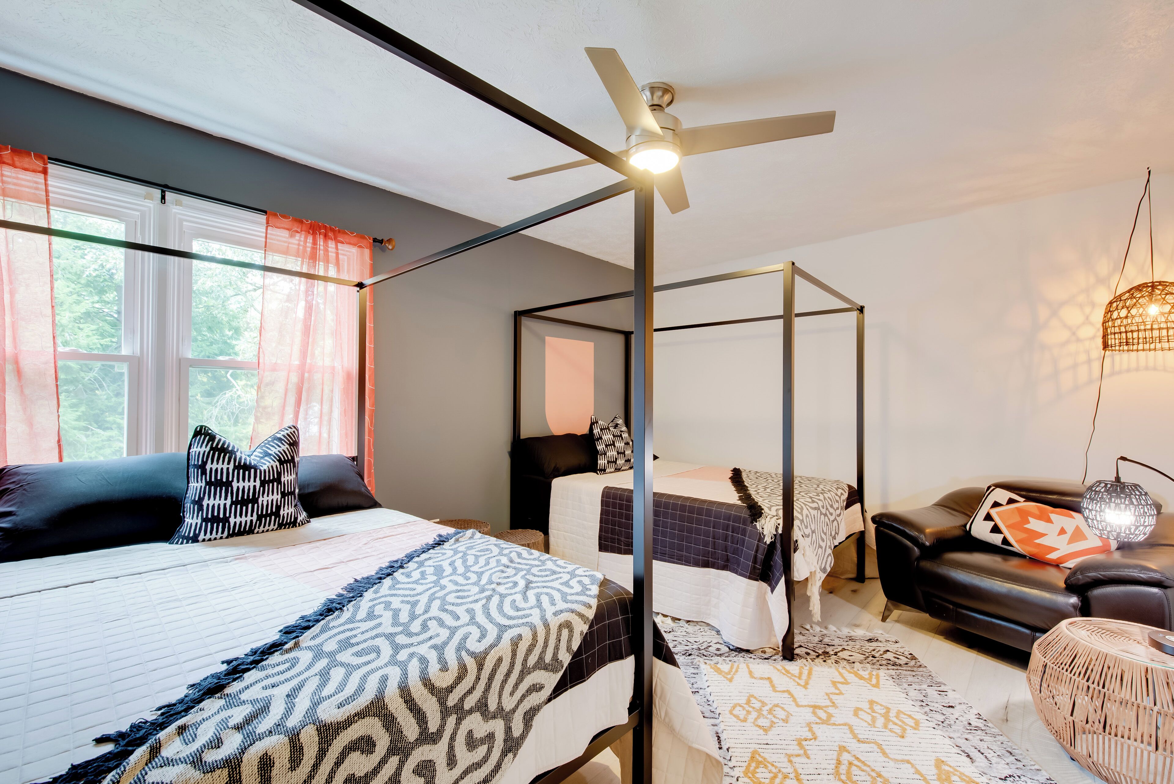 Ein Schlafzimmer mit Himmelbett, Deckenventilator und Blick ins Freie durch große Fenster.