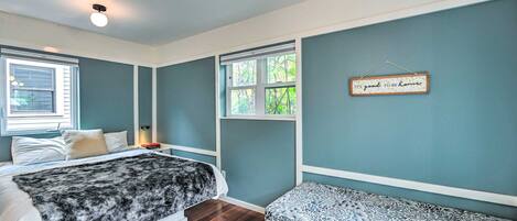 A bedroom with two beds, a window, and a wall-mounted sign.