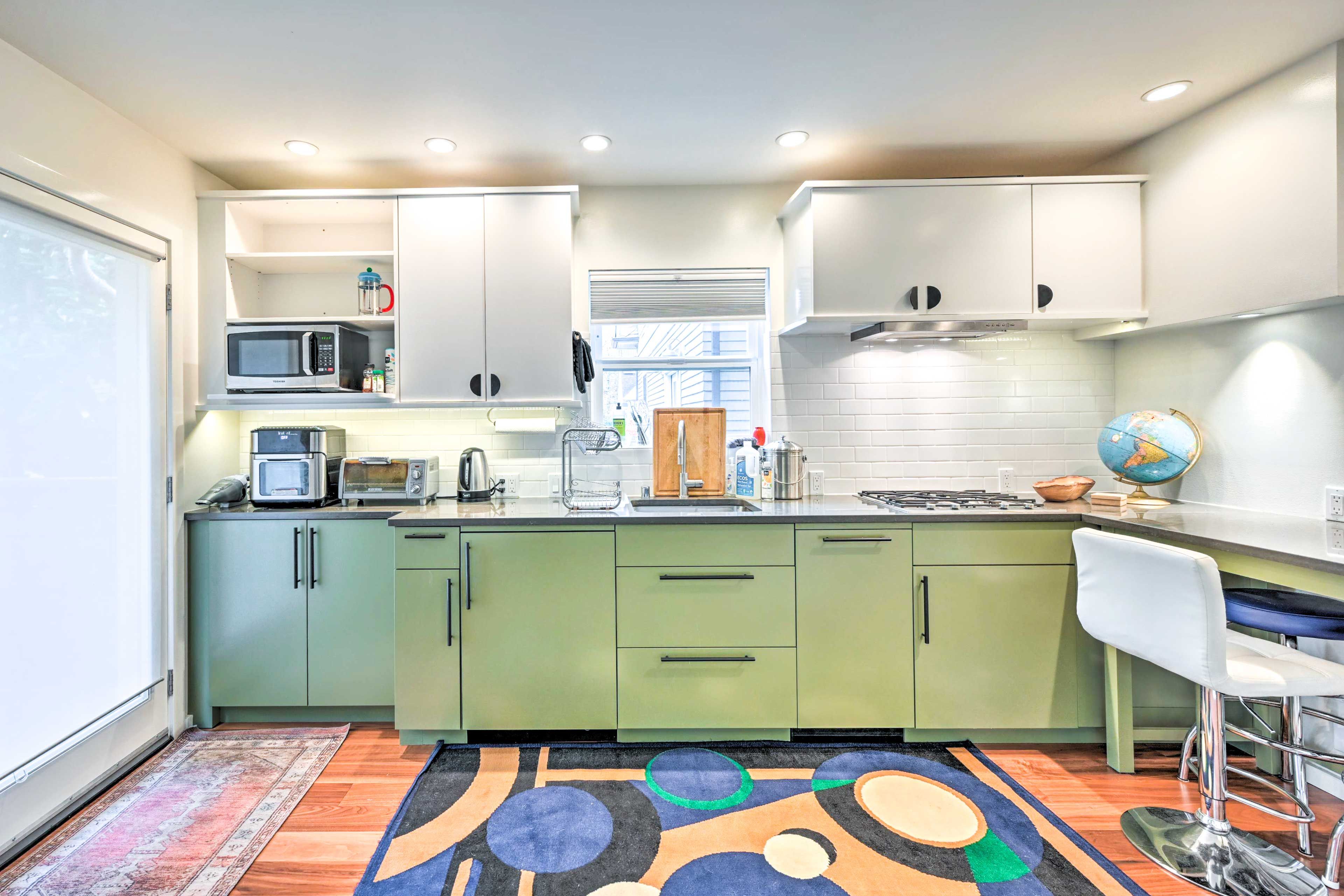 Une cuisine moderne avec des meubles de couleur verte, un four à micro-ondes, un grille-pain et un globe posé sur le plan de travail.