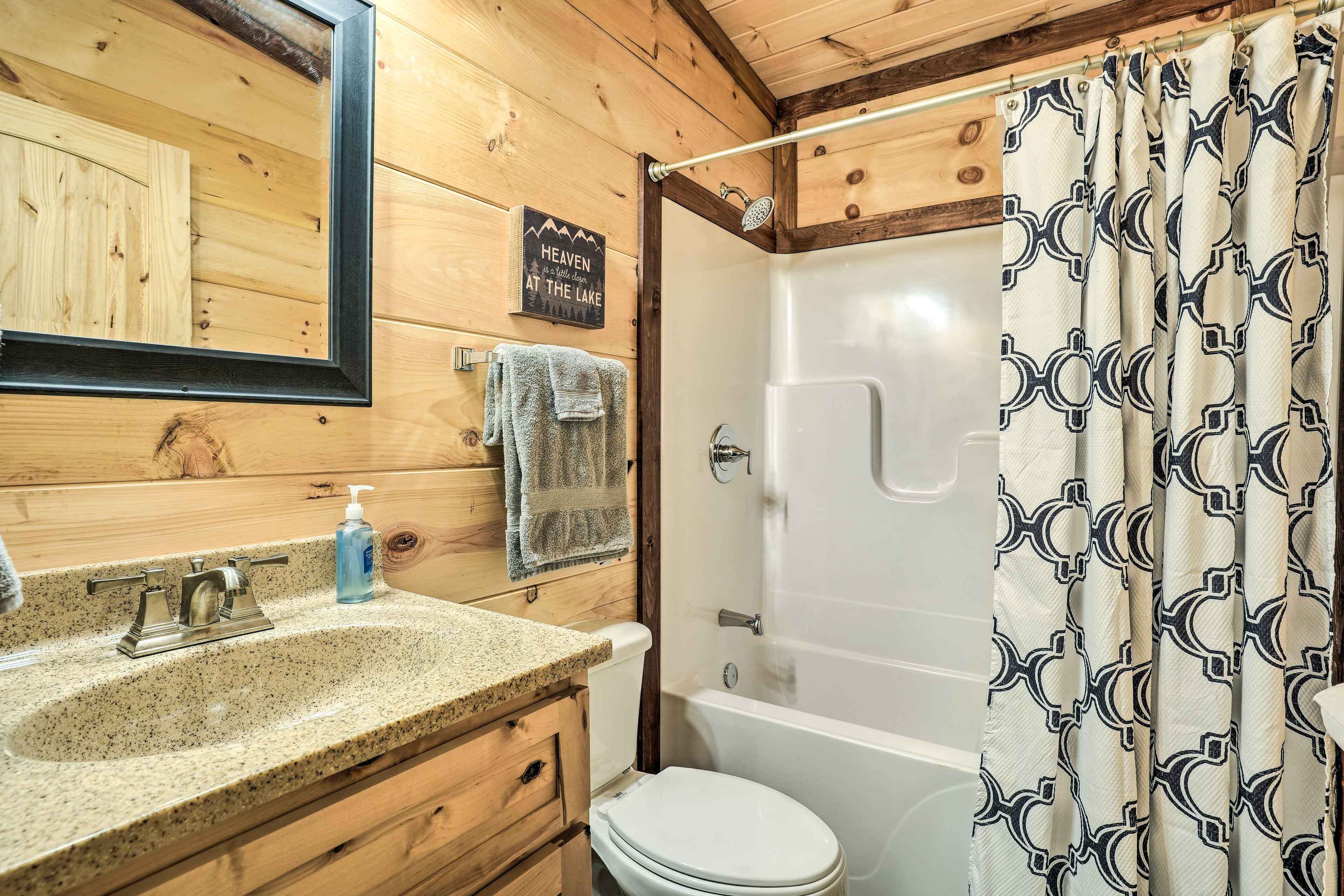 A wooden cabin bathroom with a granite sink, a toilet, and a shower.