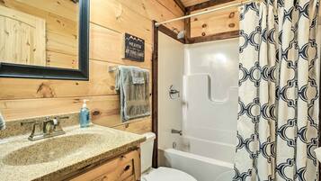 A wooden cabin bathroom with a granite sink, a toilet, and a shower.