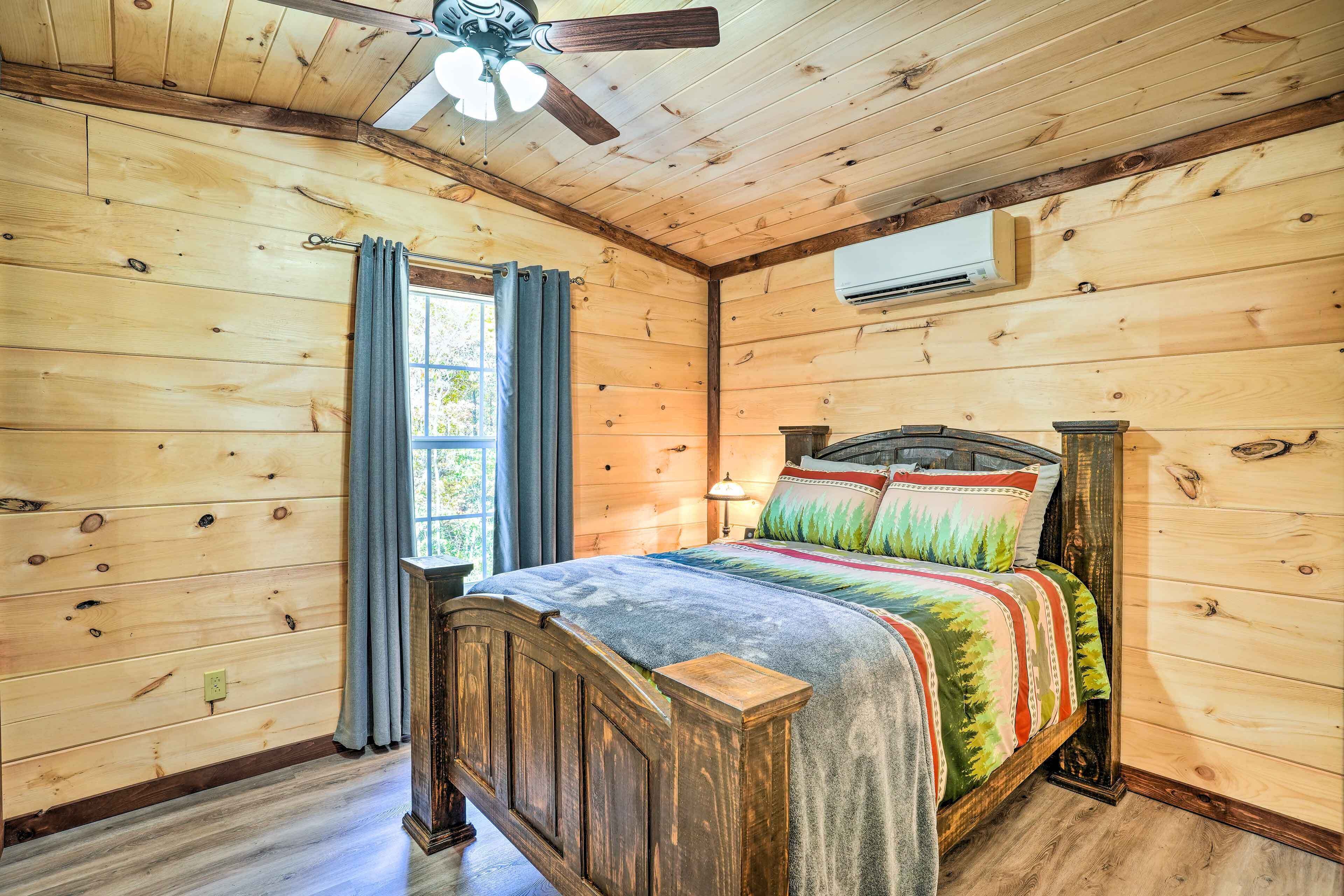 A wooden-paneled room with a bed, a ceiling fan, and an air conditioning unit.