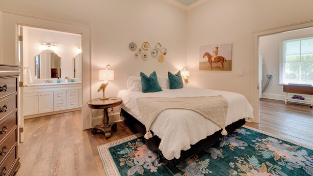 A bedroom with a bed, bedside table, lamp, wall decor, and a window. - Restored Home Near Downtown Thomasville (Thomasville)