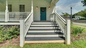 A porch with white railings and a blue door, leading to a house with a white exterior and a green roof. - Restored Home Near Downtown Thomasville (Thomasville)